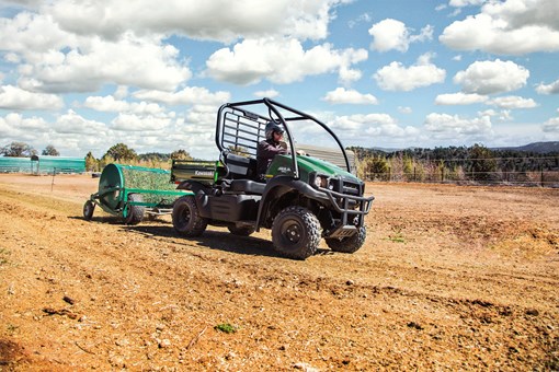 Front three-quarter angle of a person in a side x side towing a trailer through a field. opens in a new window