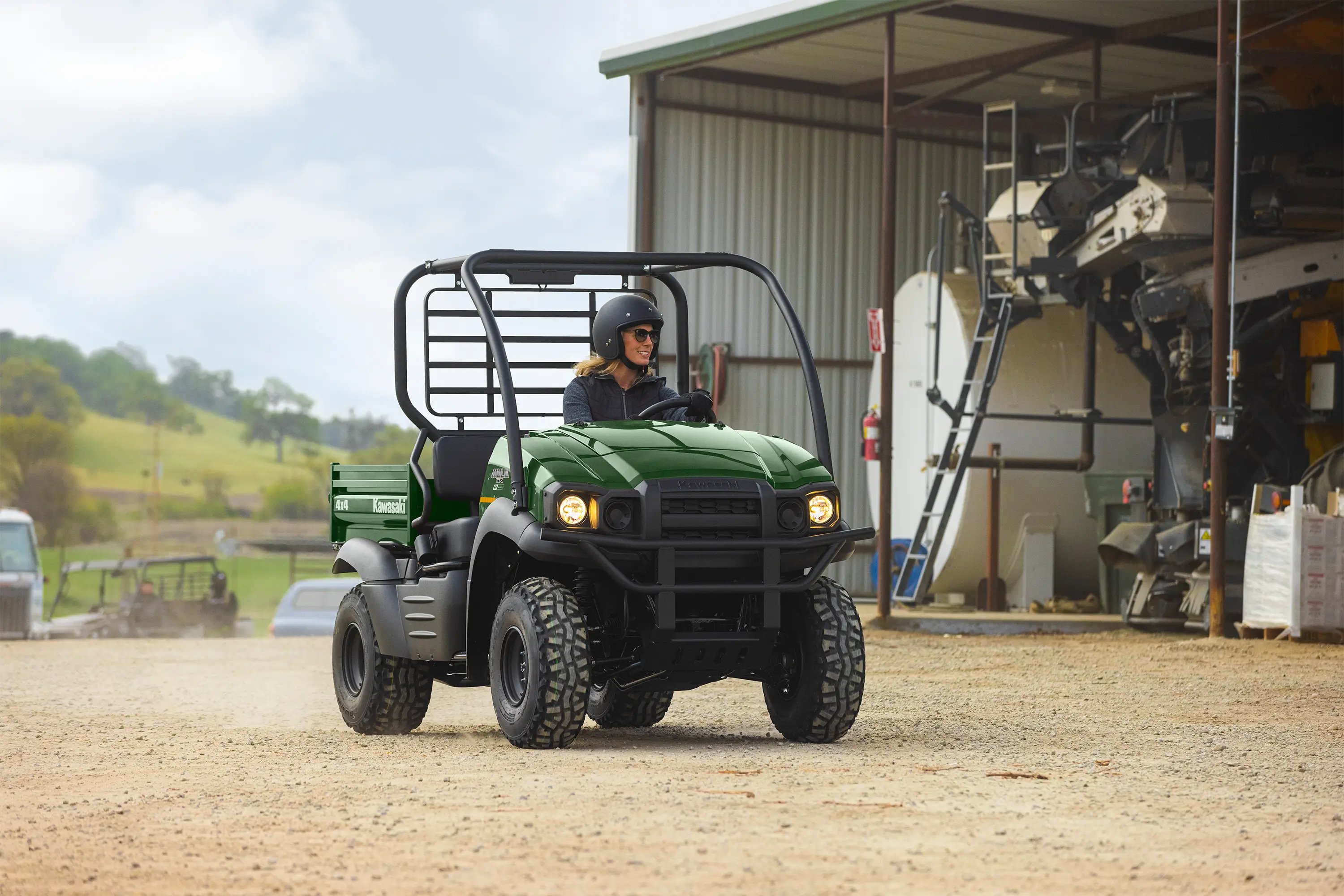 Person driving a green side x side through an industrial worksite.