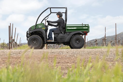 Side view of a person driving a side x side through a grassy field. opens in a new window