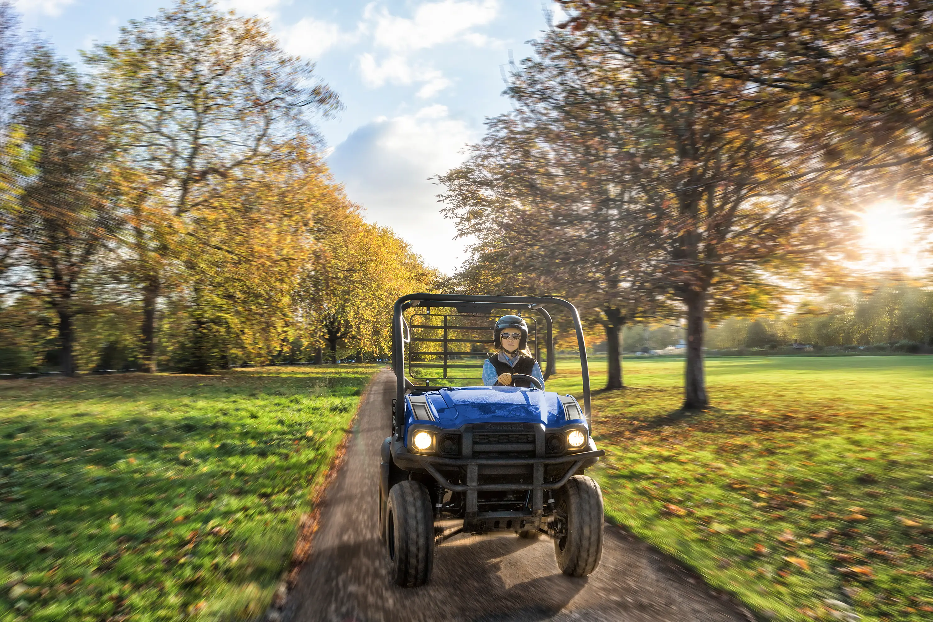 Front view of a person driving a blue side x side on a scenic country road.