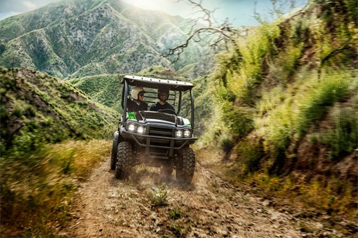 Two people riding on a rocky dirt road through the mountains in a side x side. opens in a new window