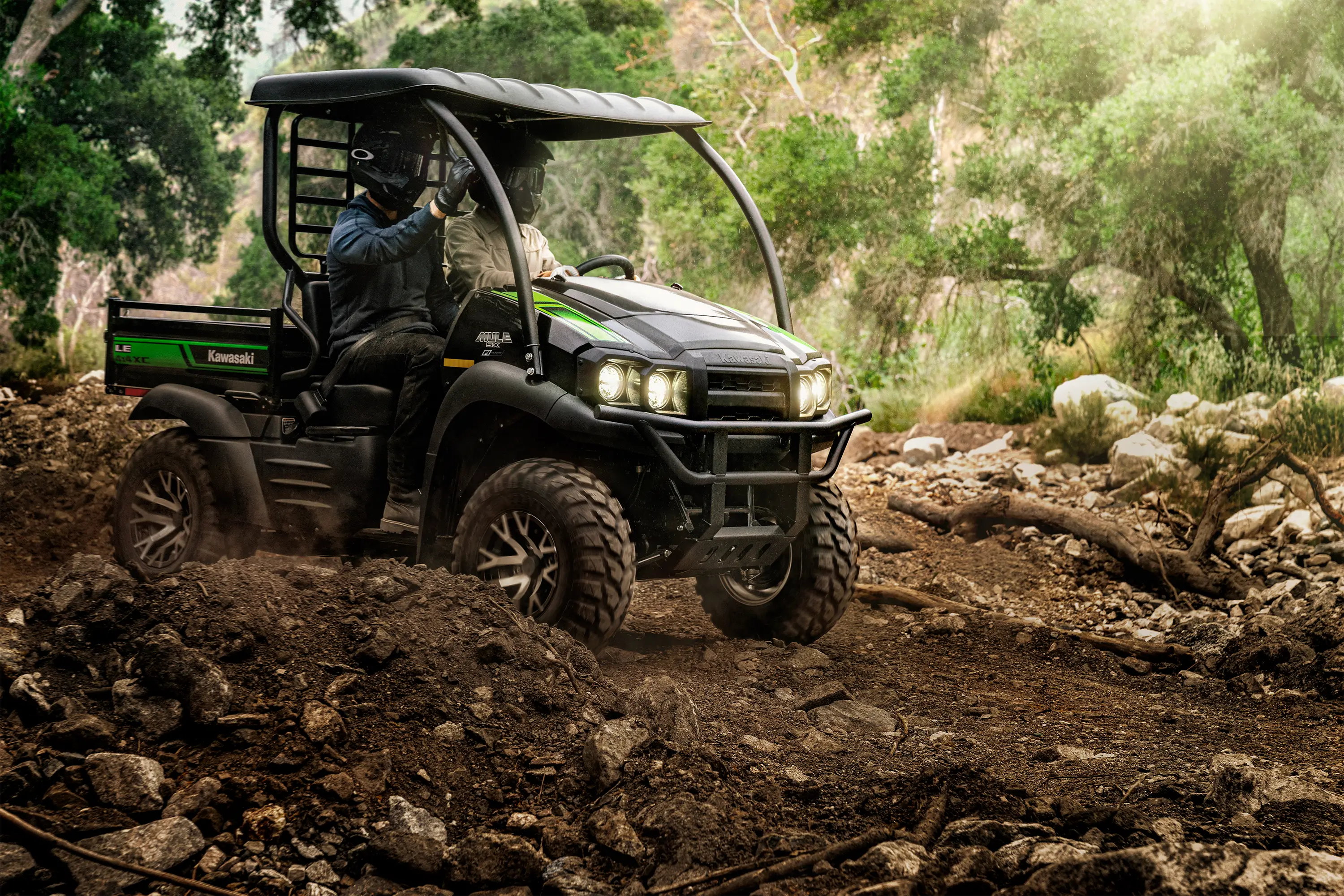 Two people riding in a side x side through rocky, uneven off-road terrain.