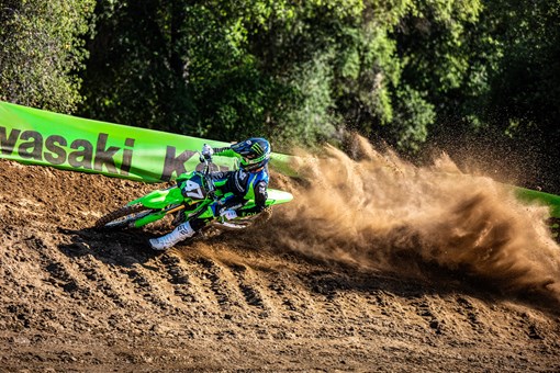Three-quarter front angle of a person riding a motorcycle around a bend on a dirt track. opens in a new window