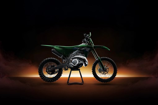 Right side view of a green dirt bike in a black studio background with glowing yellow backlighting. opens in a new window