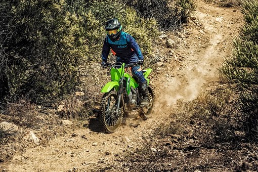 Oncoming view of a person riding a green dirt bike down a rocky trail. opens in a new window