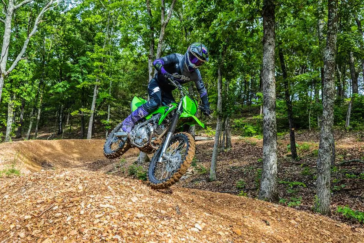 Three-quarter front angle of a person riding a motorcycle on an off-road course.