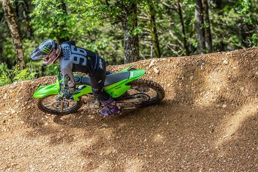Side angle of a person riding a motorcycle around a bend on an off-road course. opens in a new window