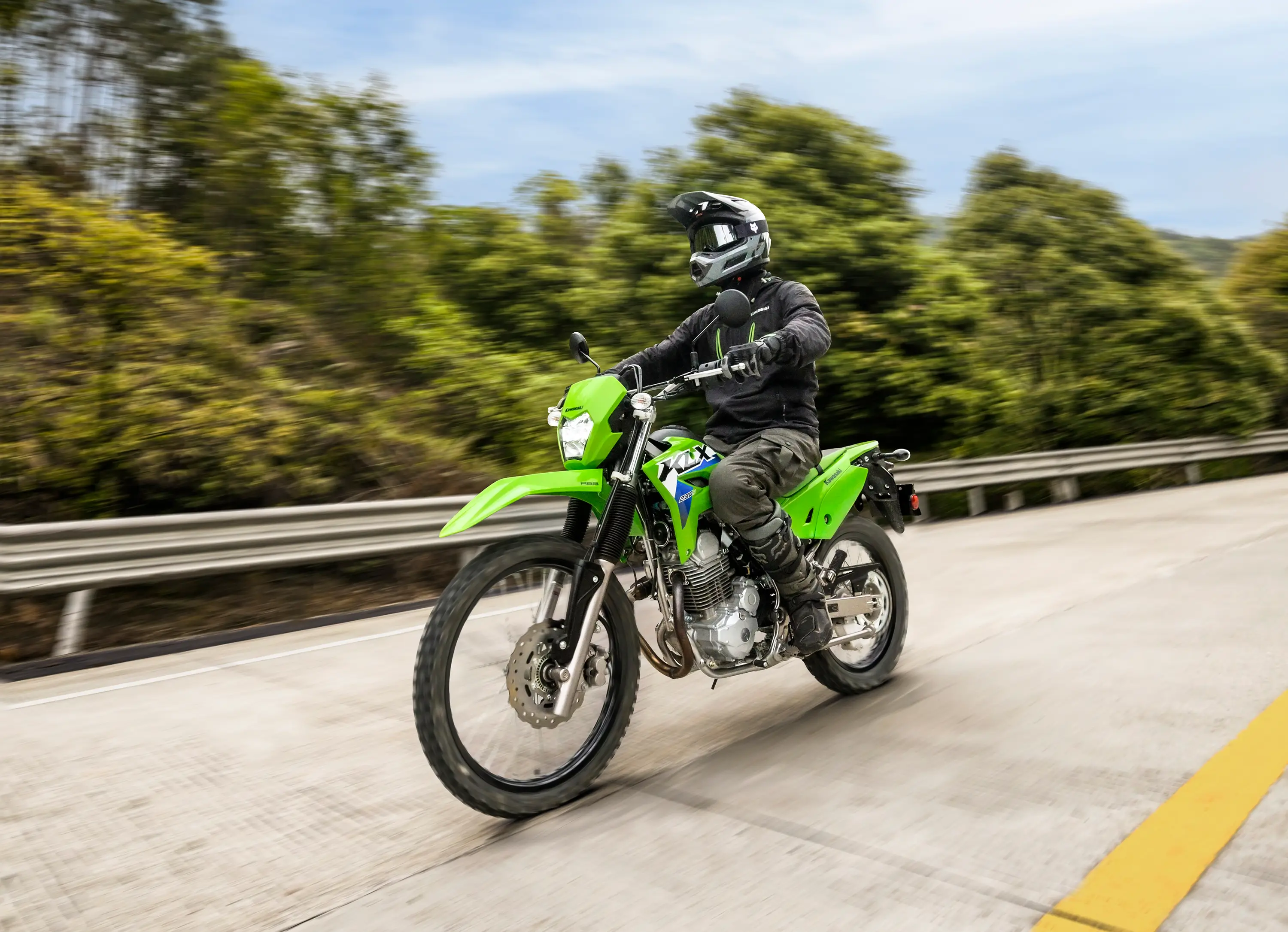 Three-quarter front angle of a person riding a motorcycle on a road.