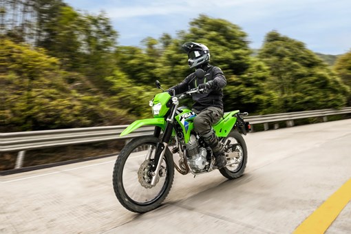 Three-quarter front angle of a person riding a motorcycle on a road. opens in a new window