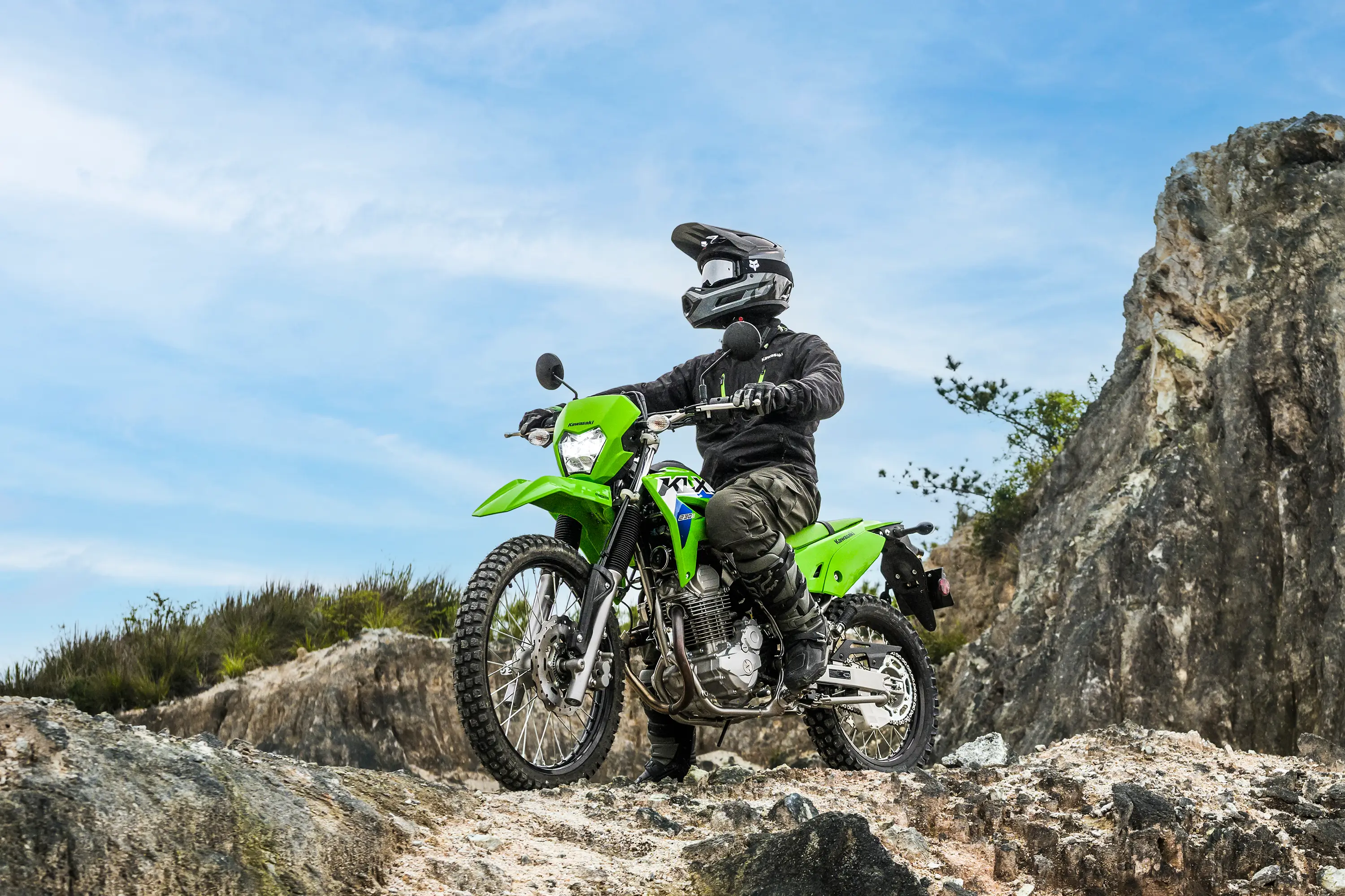 Three-quarter front angle of a person seated on a motorcycle off-road.