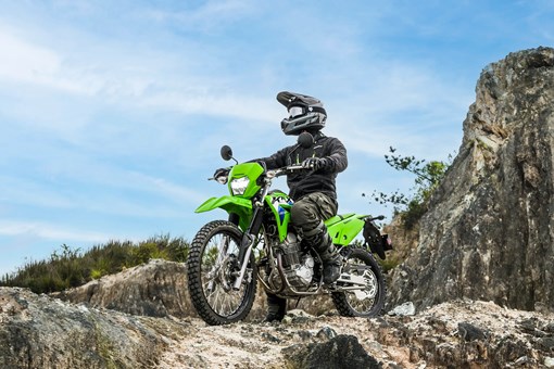 Three-quarter front angle of a person seated on a motorcycle off-road. opens in a new window