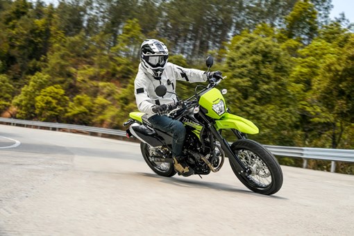 Three-quarter front angle of a person riding a motorcycle around a bend on a road. opens in a new window