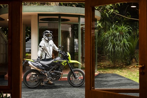 Side angle of a person standing next to a motorcycle. opens in a new window