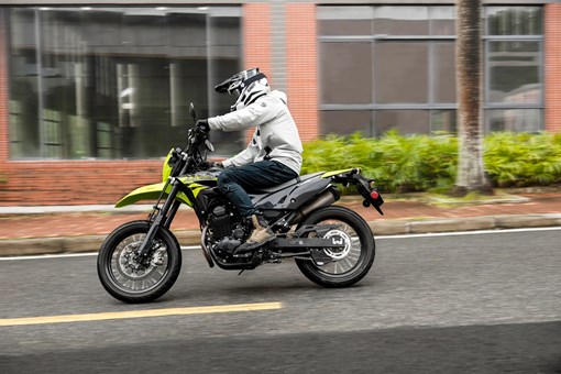Profile angle of a person riding a motorcycle on a city street. opens in a new window