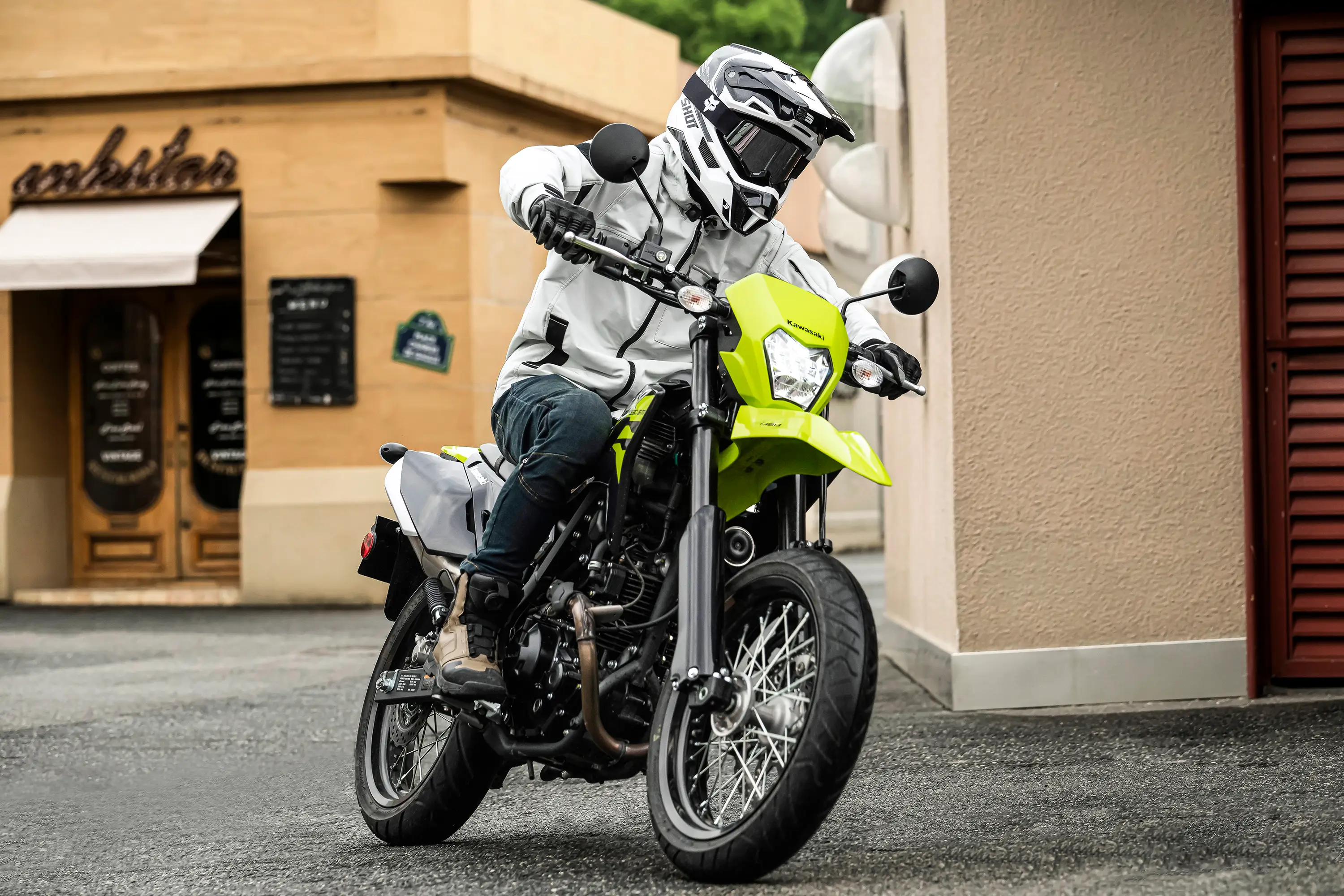 Three-quarter front angle of a person riding a motorcycle on a city street.