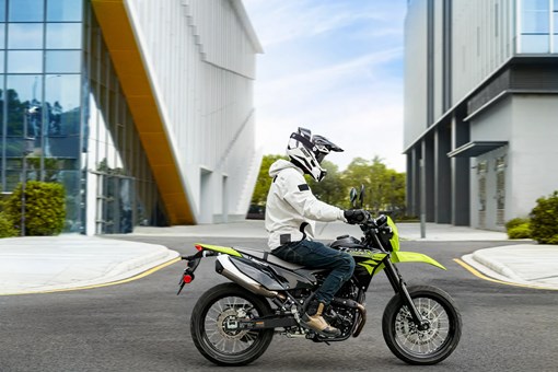 Side angle of a person riding a motorcycle on a city street. opens in a new window