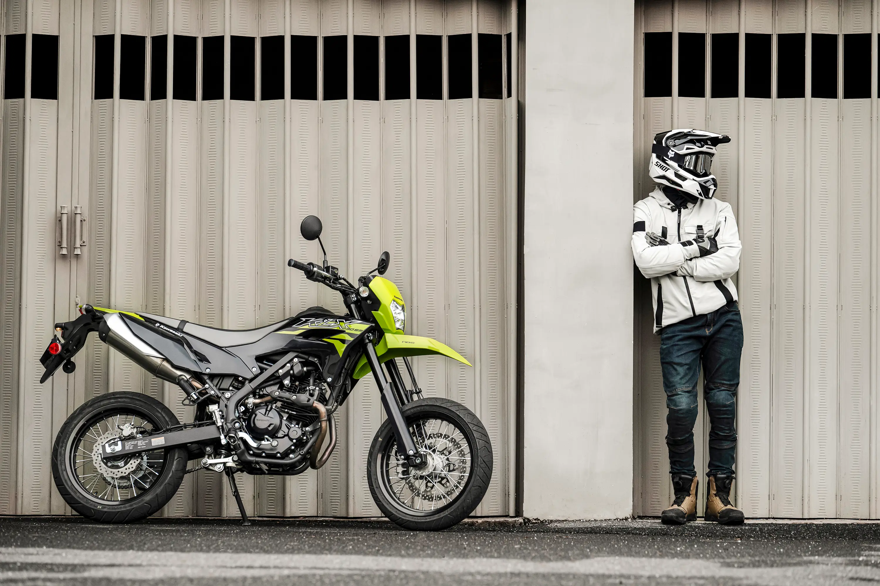 Profile angle of a person standing next to a motorcycle.