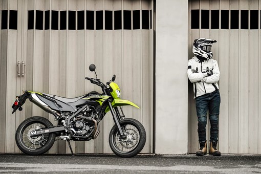 Profile angle of a person standing next to a motorcycle. opens in a new window