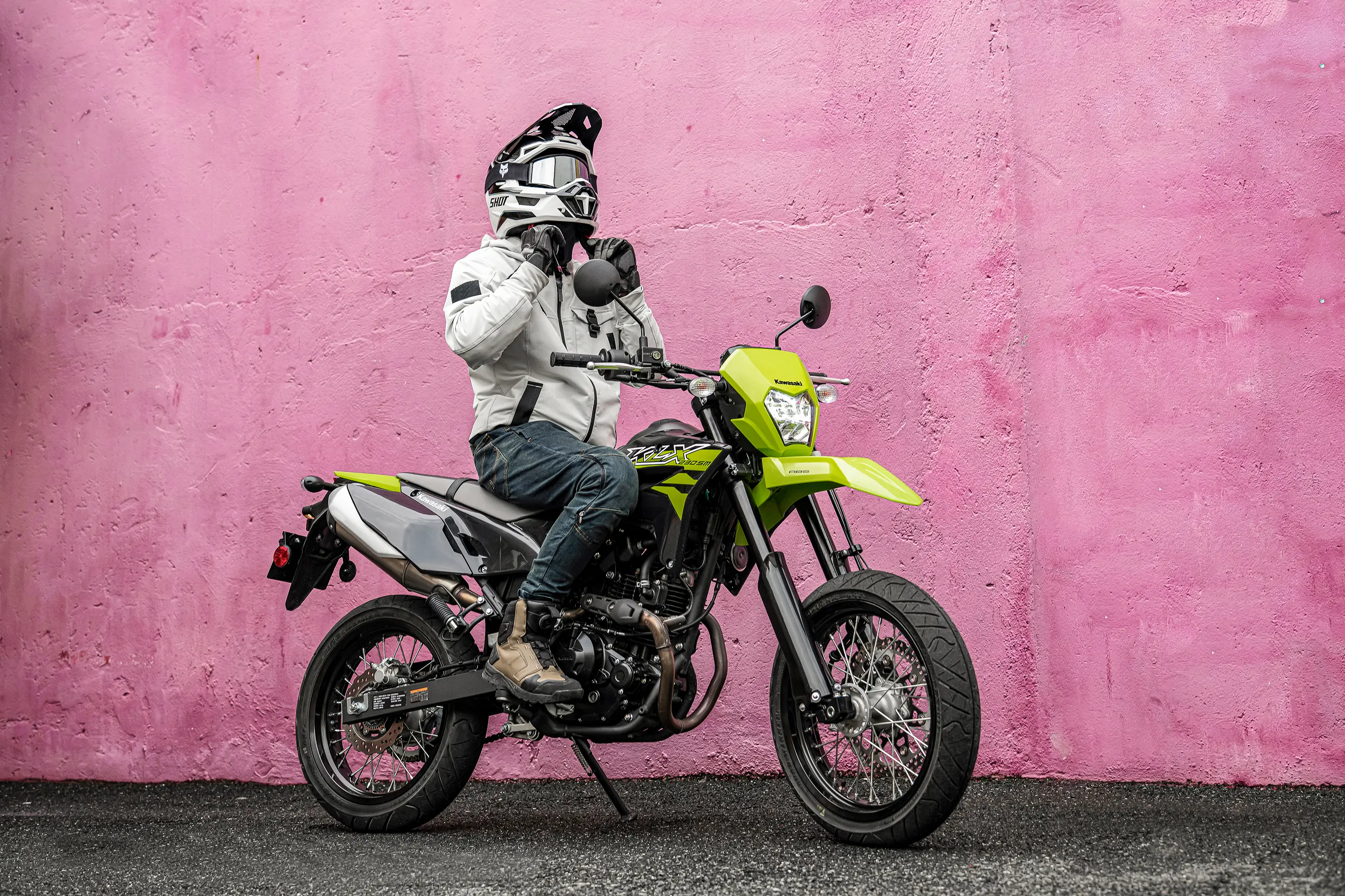 Side angle of a person seated on a parked motorcycle.