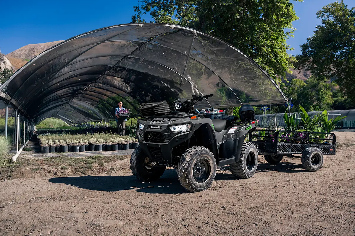A utility ATV and trailer parked in front of a garden nursery.