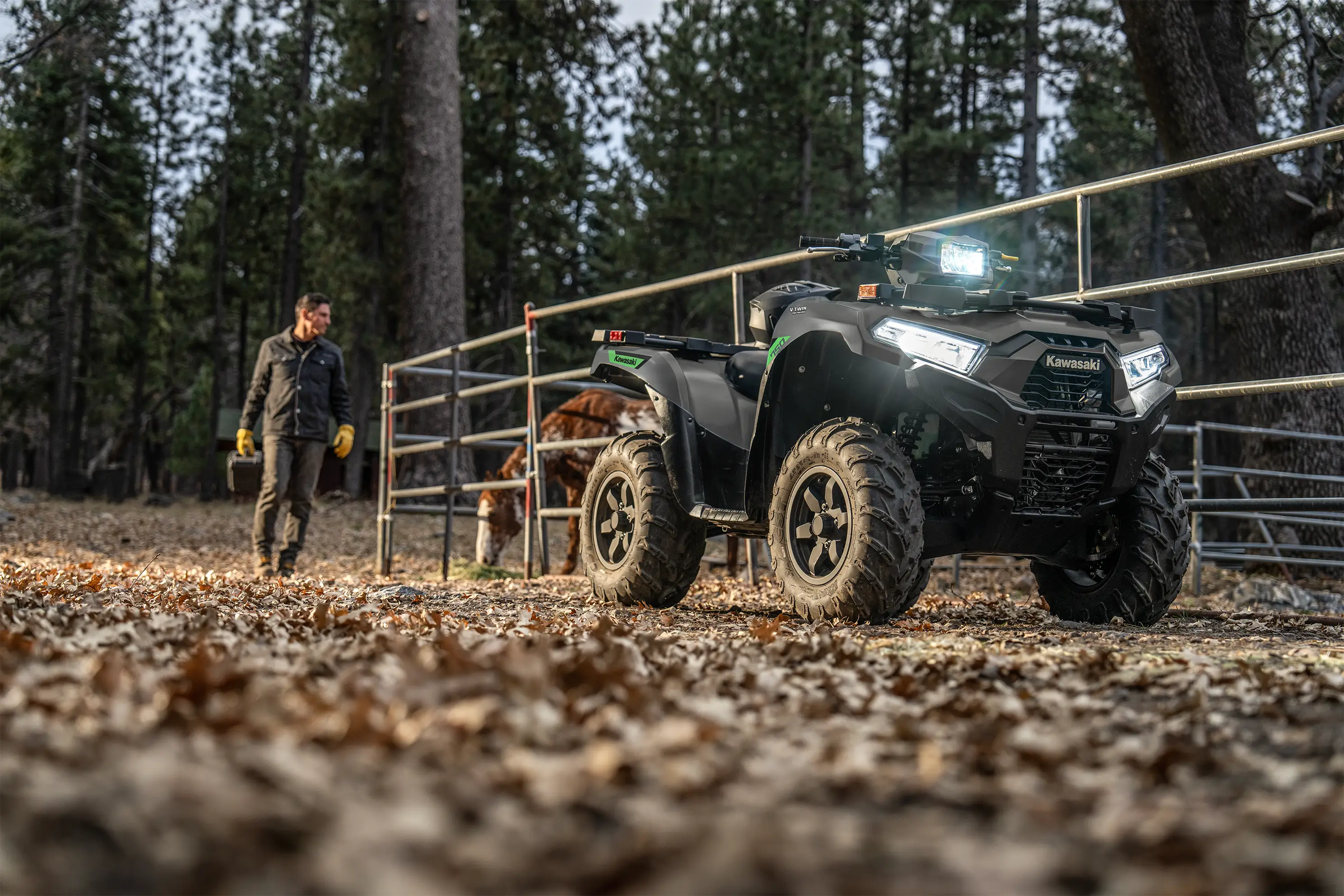 Utility ATV parked in front of a horse corral with a person in the background.