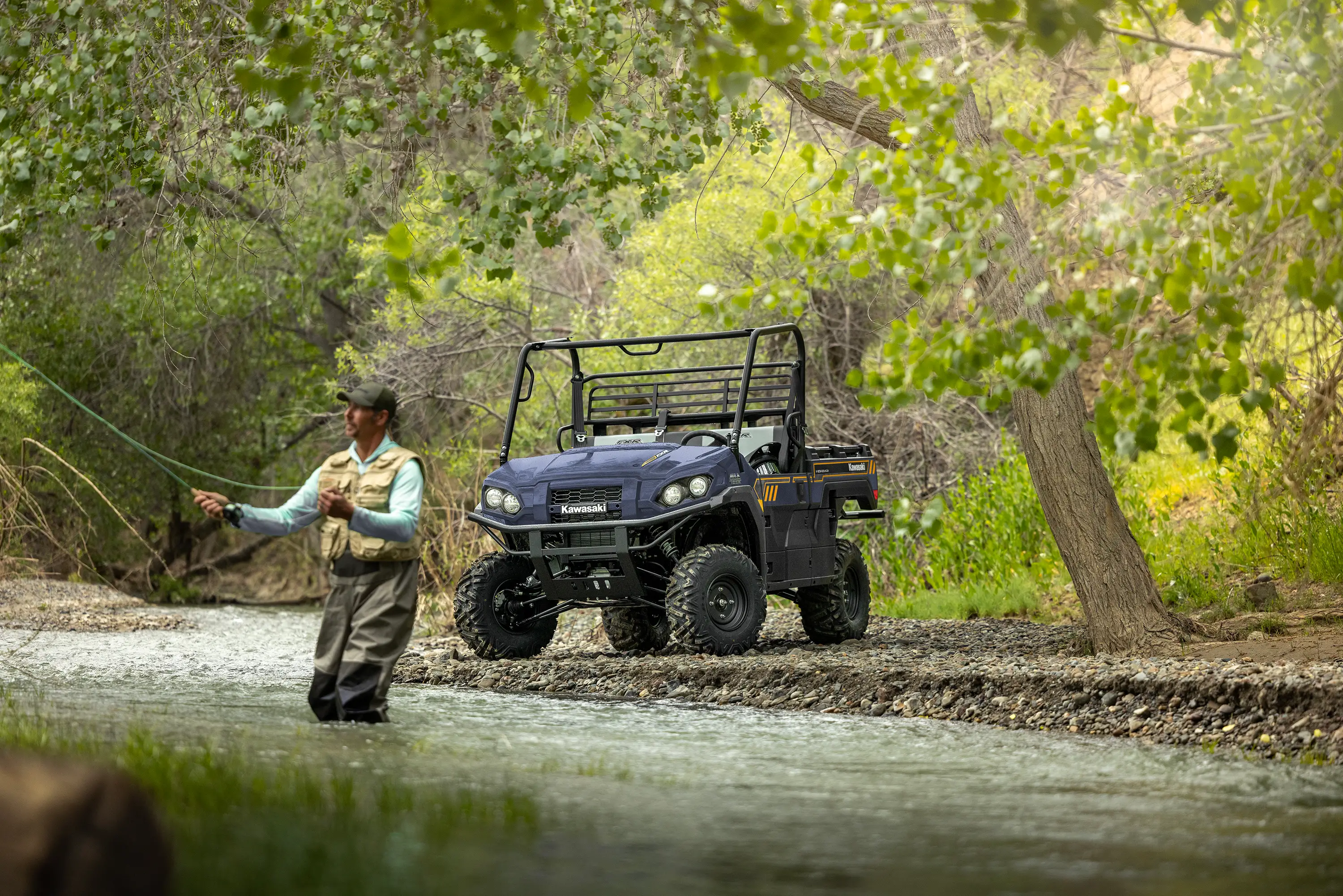 Person fly fishing in a river with a side x side parked in the background.