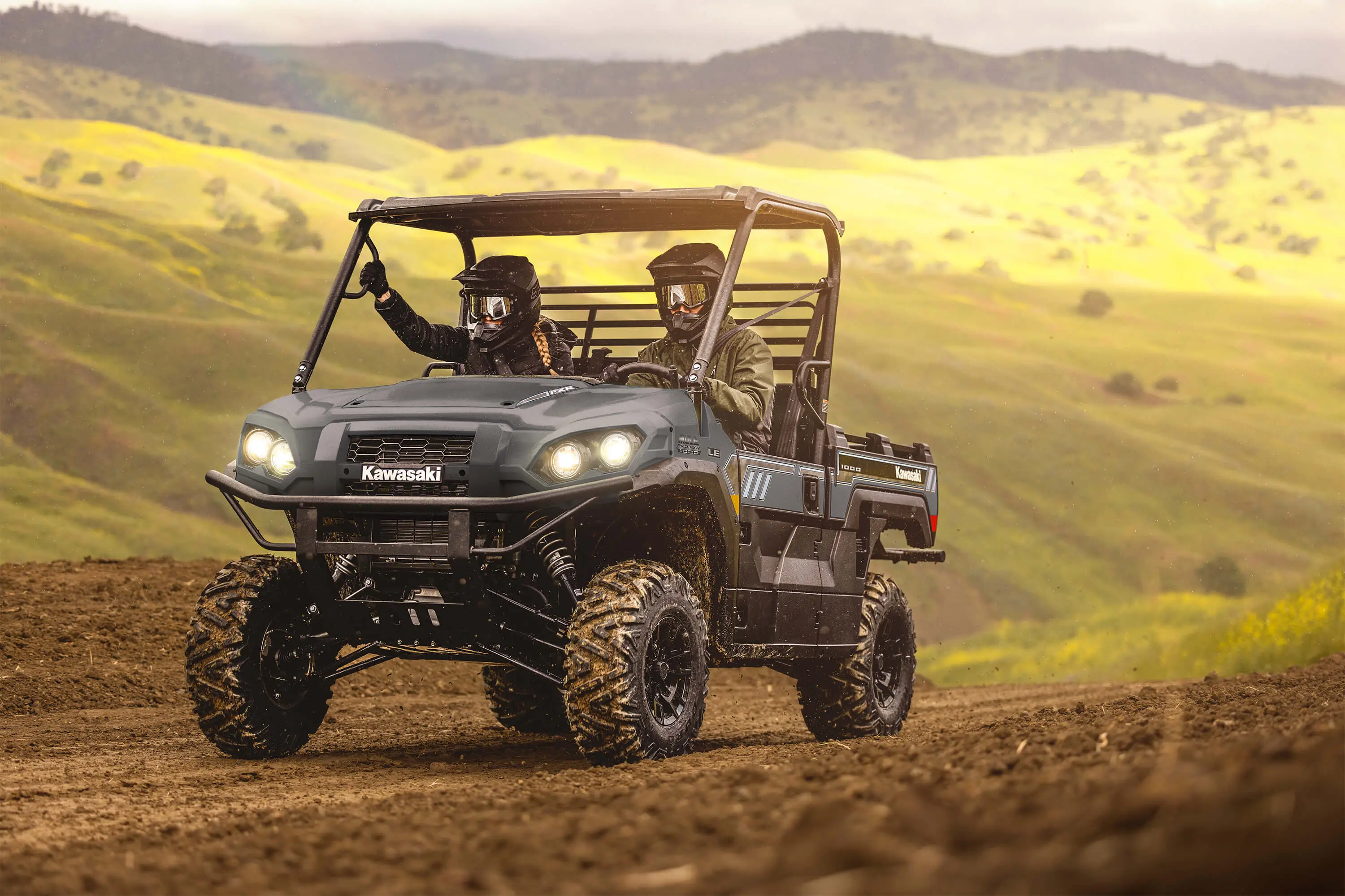 Two people in a side x side driving up a country road.