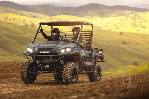 Two people in a side x side driving up a country road. opens in a new window