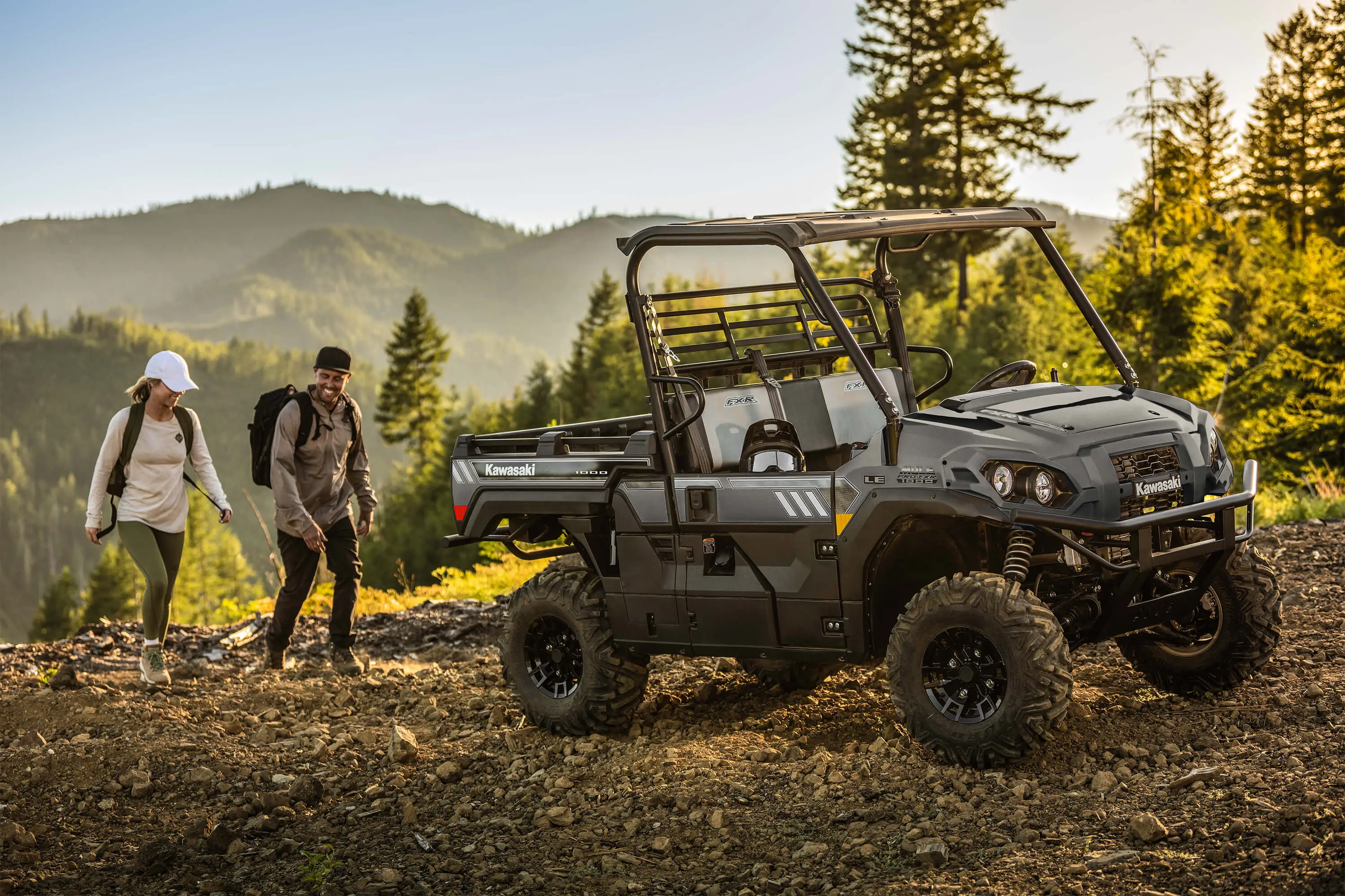 Side x side parked on a mountain top with two hikers in the background.
