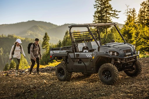 Side x side parked on a mountain top with two hikers in the background. opens in a new window