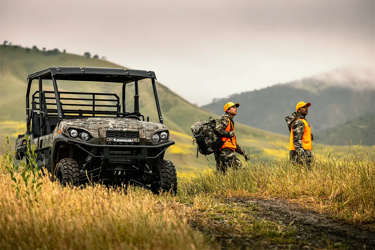 Scenic photo of a side x side on a dirt road with people in hunting gear.