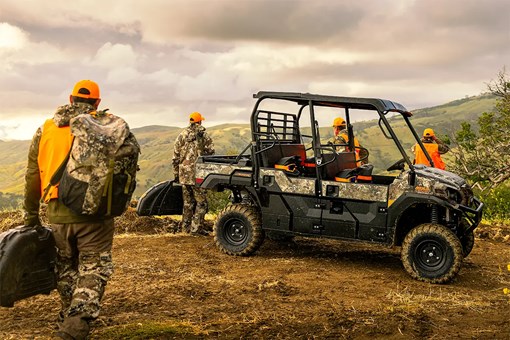 People with hunting gear walking toward a side x side parked on a hilltop. opens in a new window
