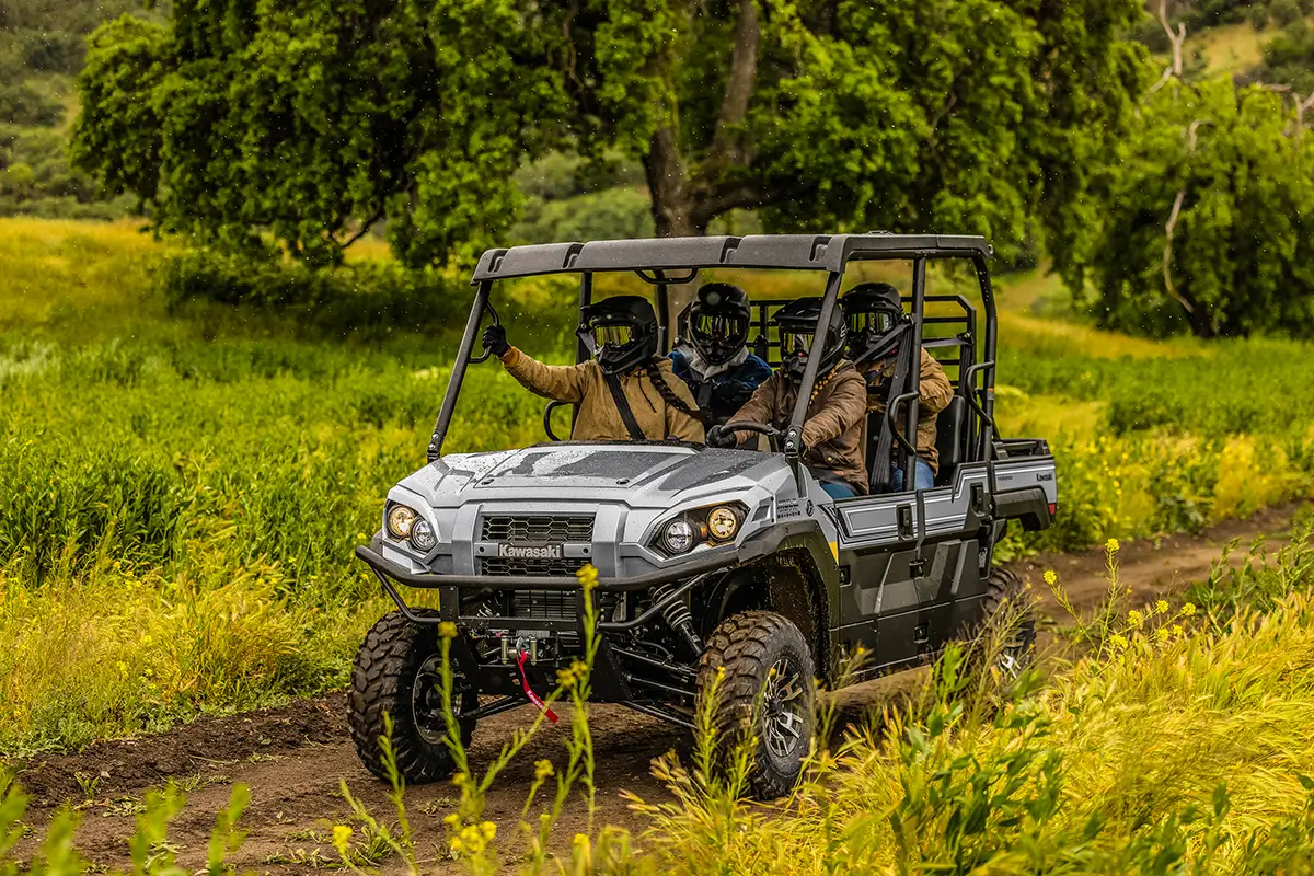 Four people riding in a side x side on a dirt road and rain.
