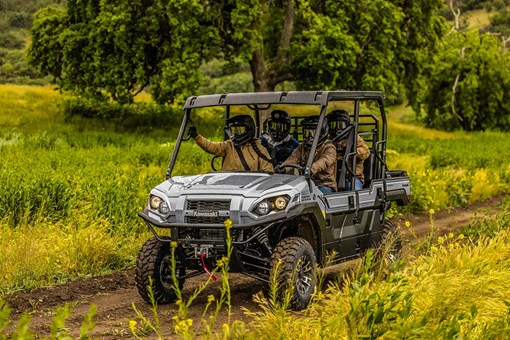 Four people riding in a side x side on a dirt road and rain. opens in a new window