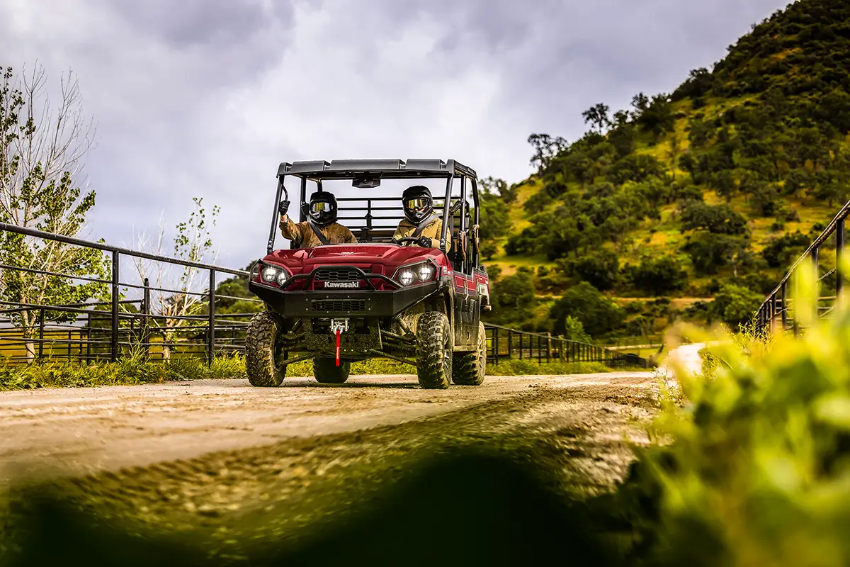 Two people riding in a red side x side on a ranch.