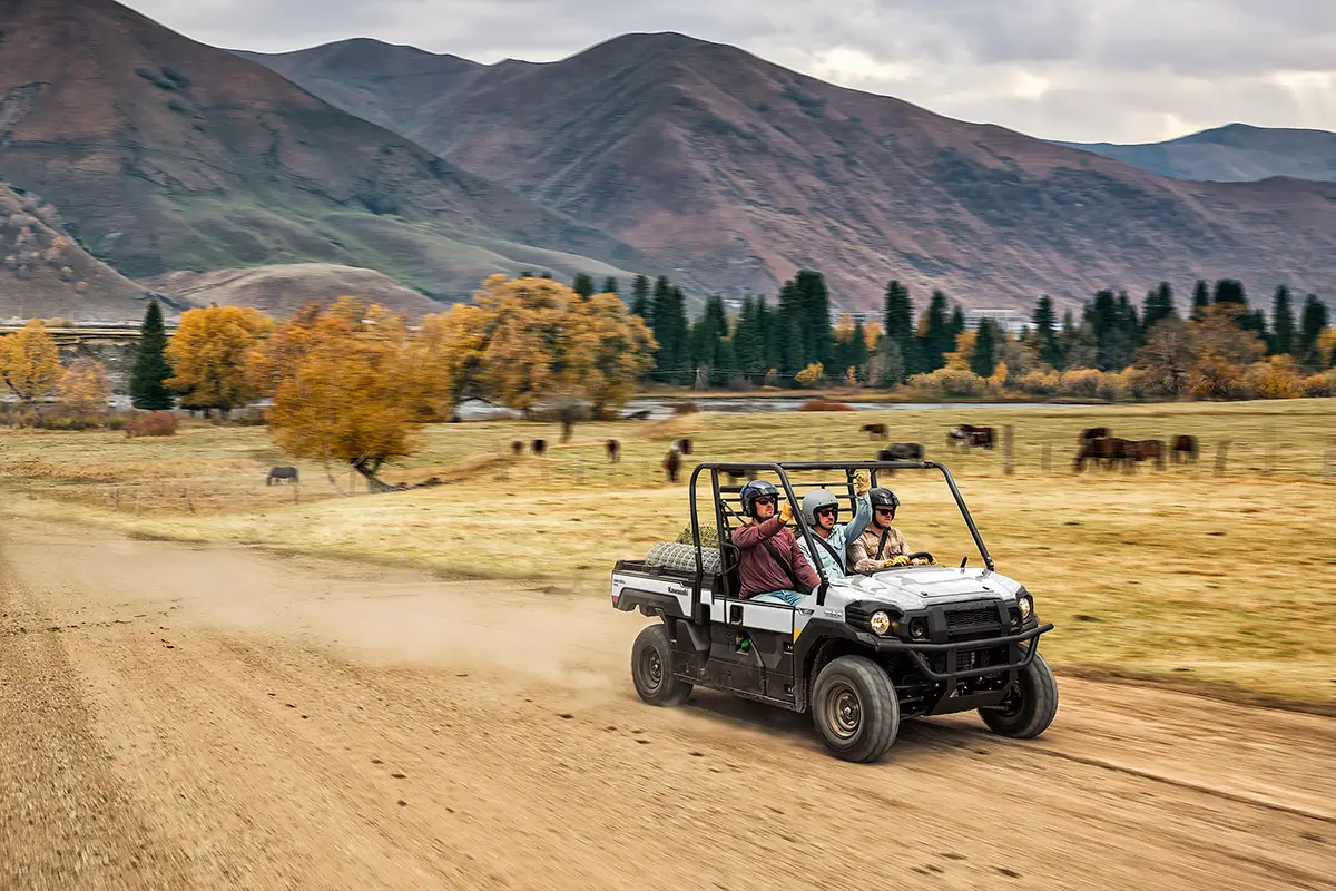 Scenic view of people riding in a side x side on a ranch in the mountains.