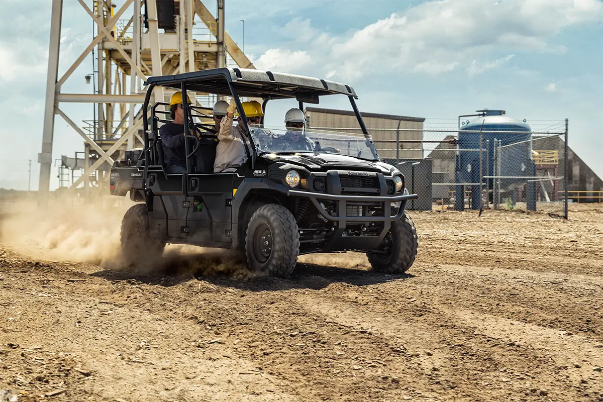 People riding in a side x side on an industrial worksite.