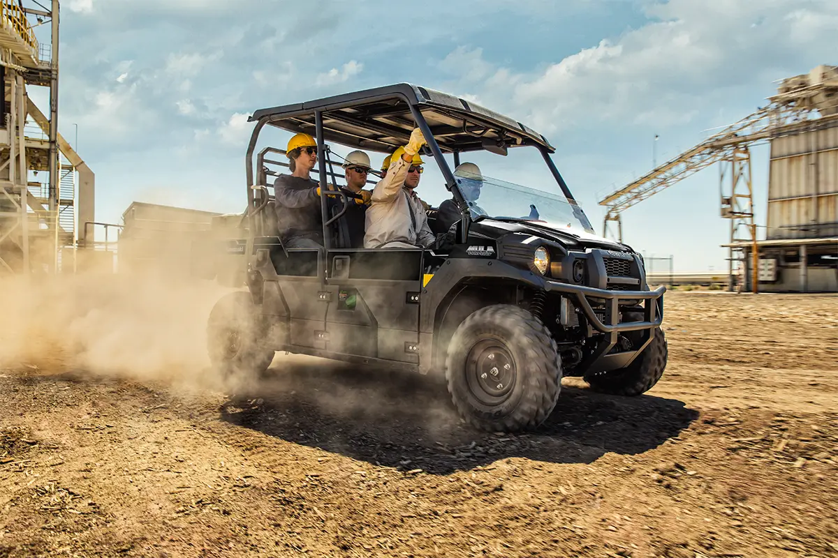 Three-quarter front angle of five people riding in a black side x side at a jobsite.