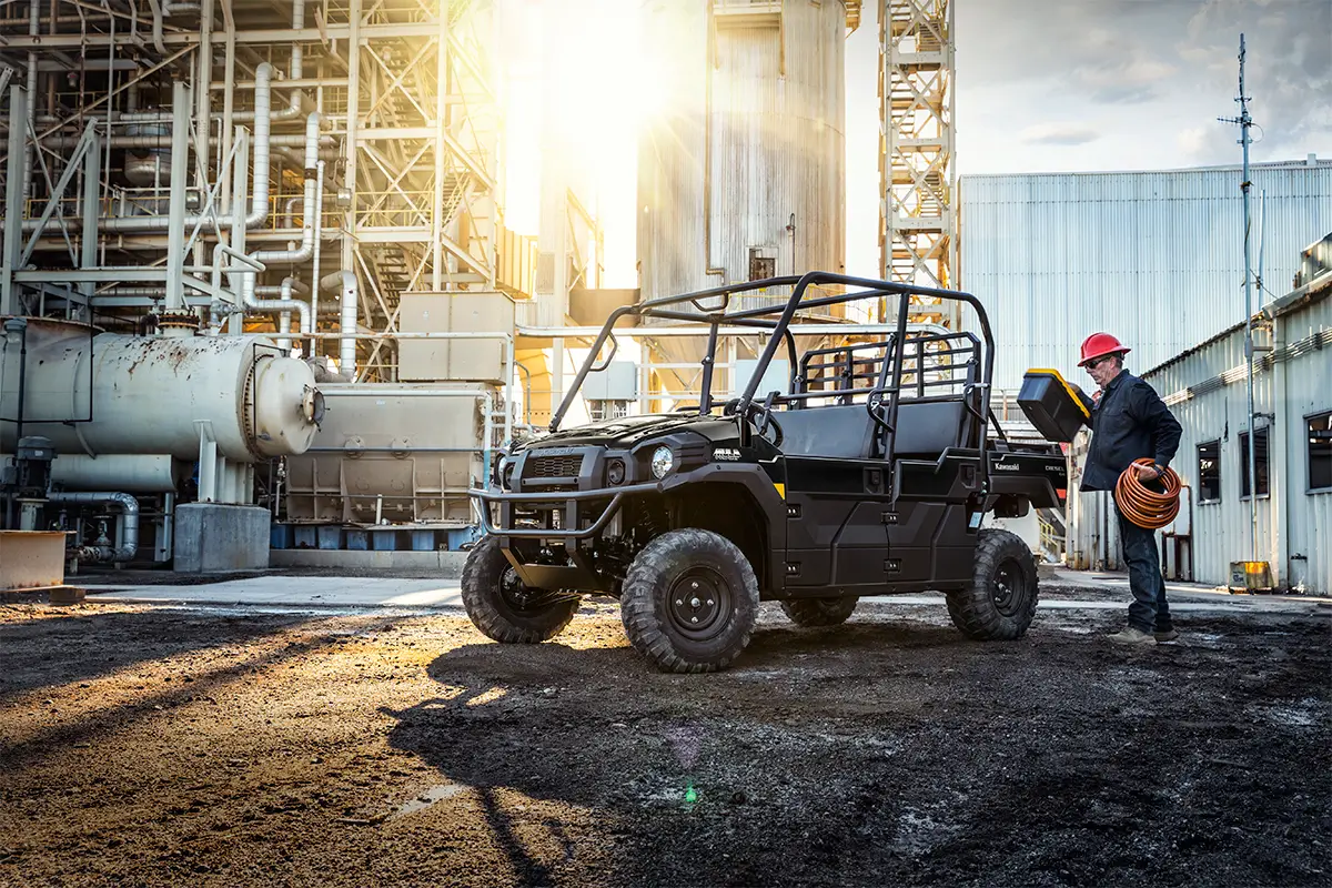 Three-quarter front angle of a person loading the bed of a parked side x side at a jobsite.