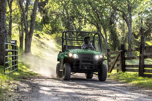 Person driving a green side x side down a dirt road under trees. opens in a new window