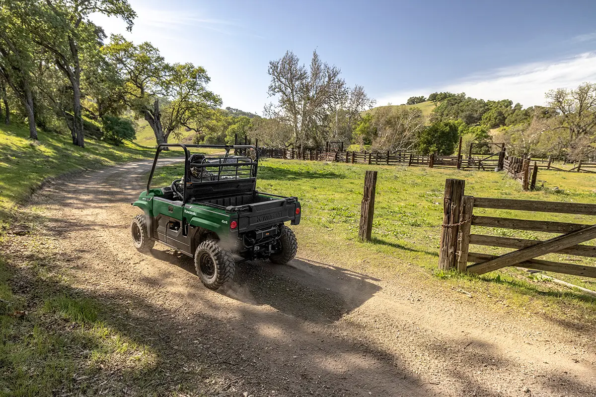 Rear three-quarter view of a green side x side on a country road.