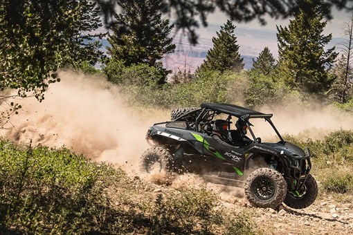Side angle of two people driving a side x side off-road. opens in a new window