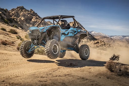 Three-quarter front angle of a person riding a side x side off-road. opens in a new window