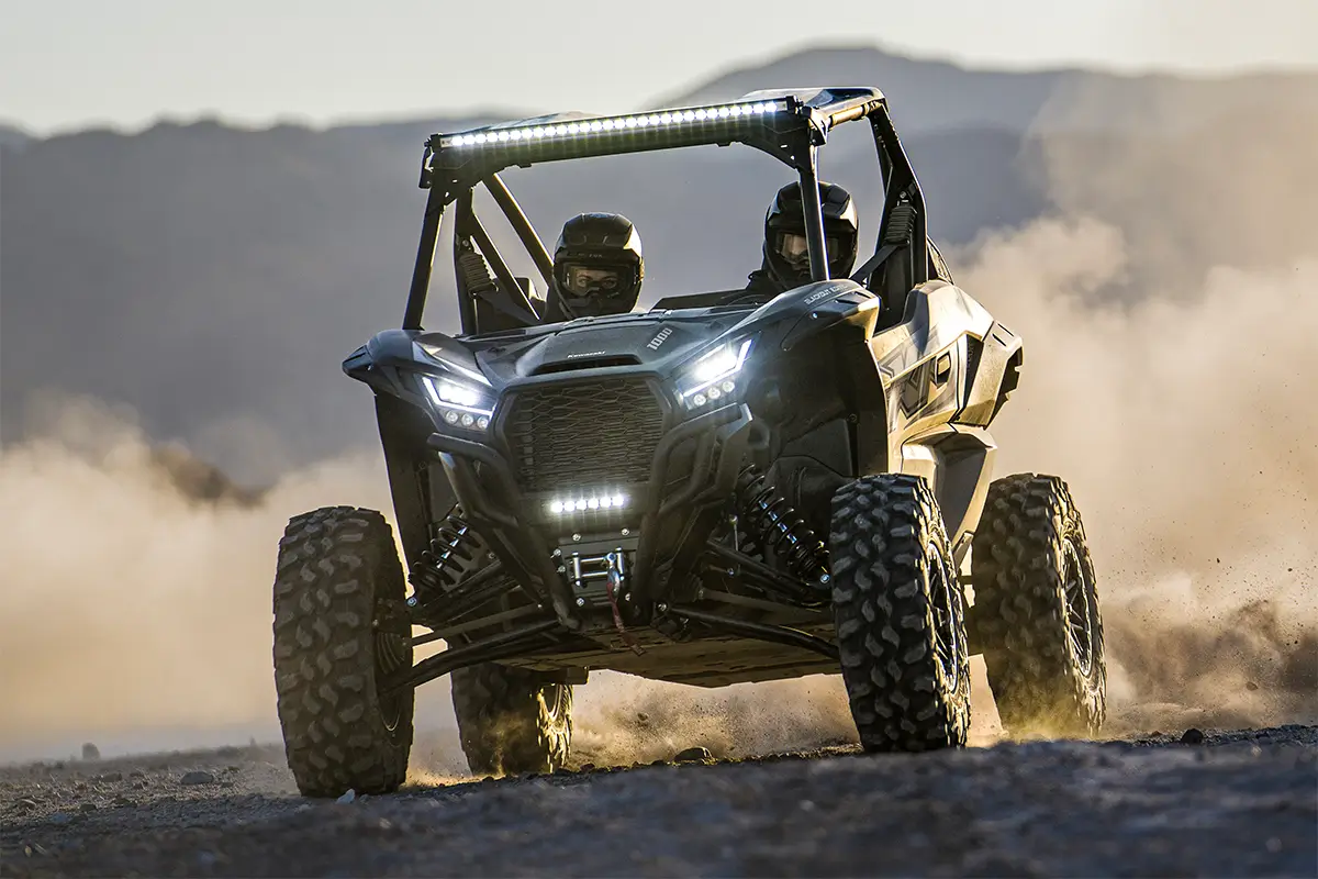 Front angle of two people driving a side x side off-road.