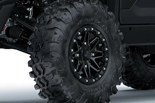 Close-up of the front-left wheel of a side x side staged in a white studio background. opens in a new window