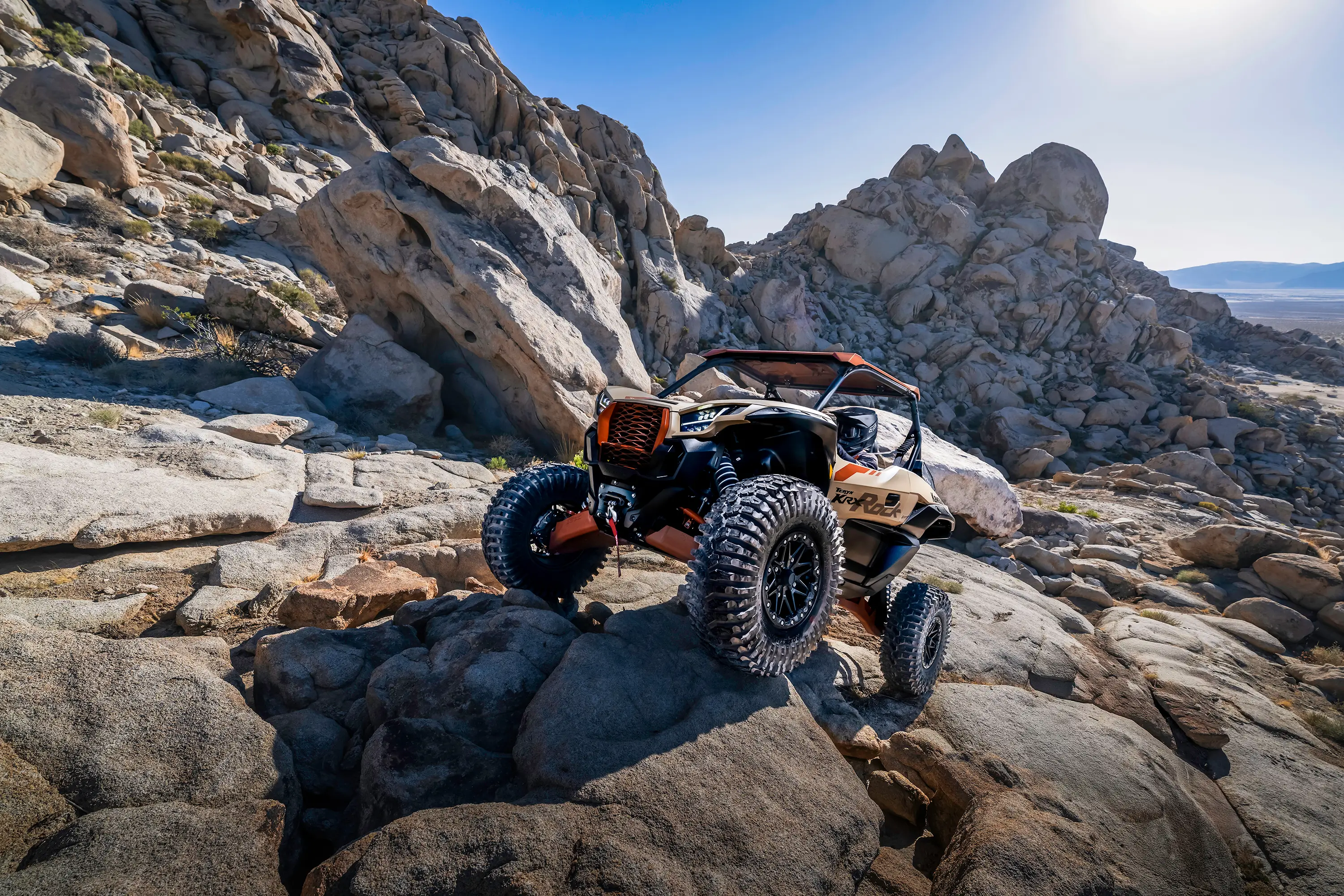 Three-quarter front angle of a person driving through a rock garden in a side x side.