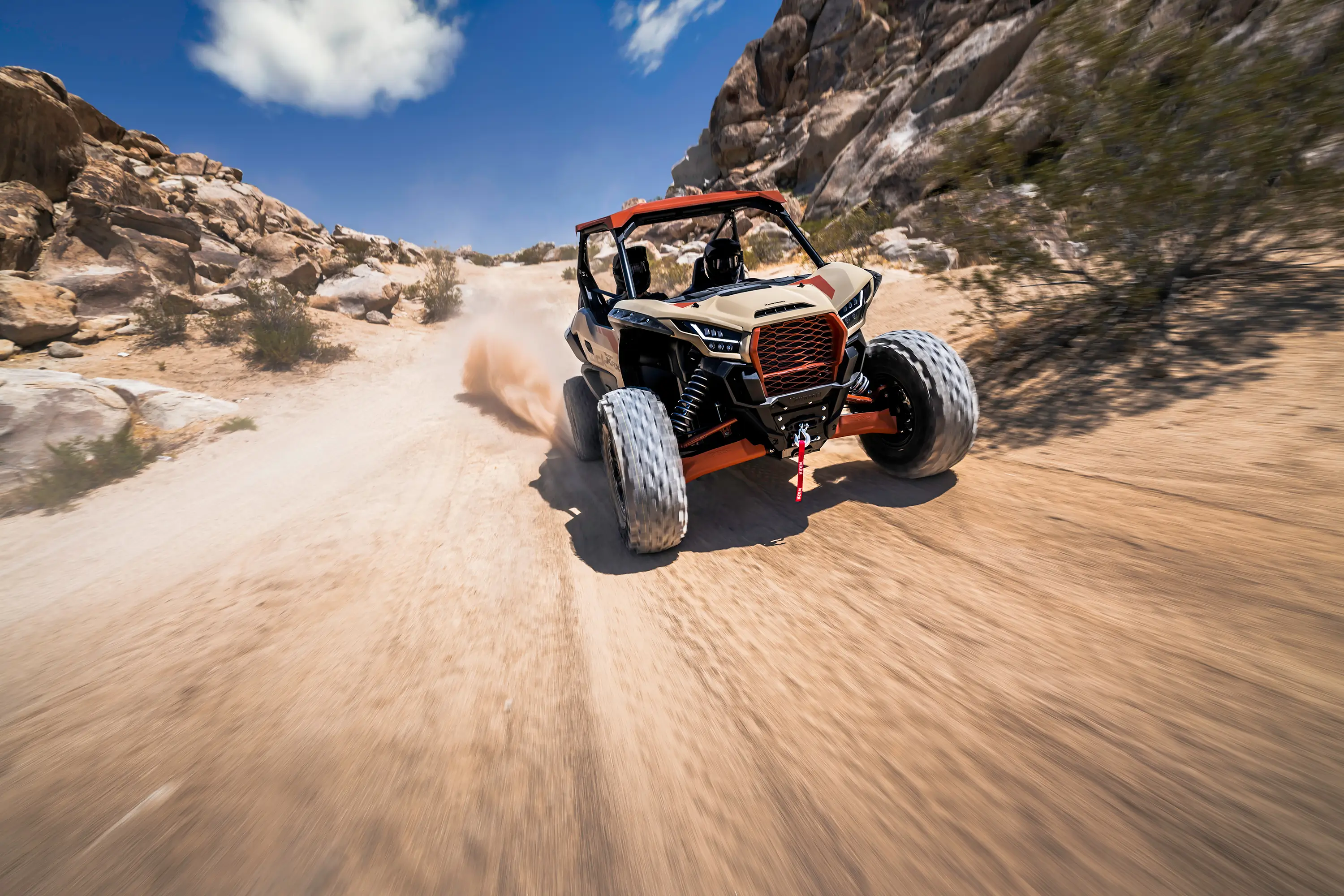 Front angle of two people riding a side x side off-road.