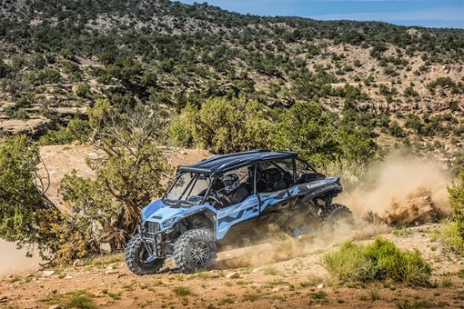 Side angle of four people driving a side x side off-road. opens in a new window