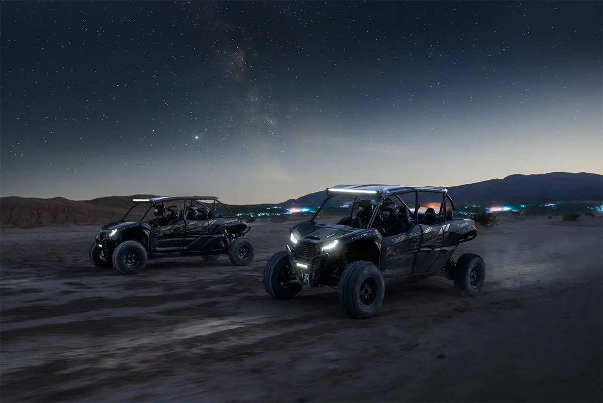 Three-quarter front angle of two parties driving separate side x sides off-road.