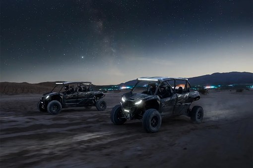 Three-quarter front angle of two parties driving separate side x sides off-road. opens in a new window